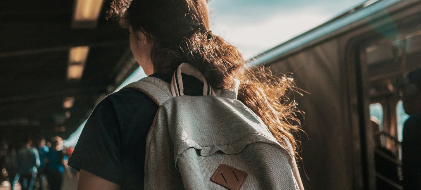 Persona de espaldas con mochila en estación de tren