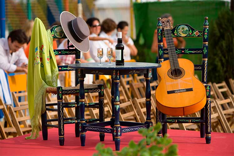 Tablao flamenco con mesa, sillas de enea, un mantoncillo y una guitarra